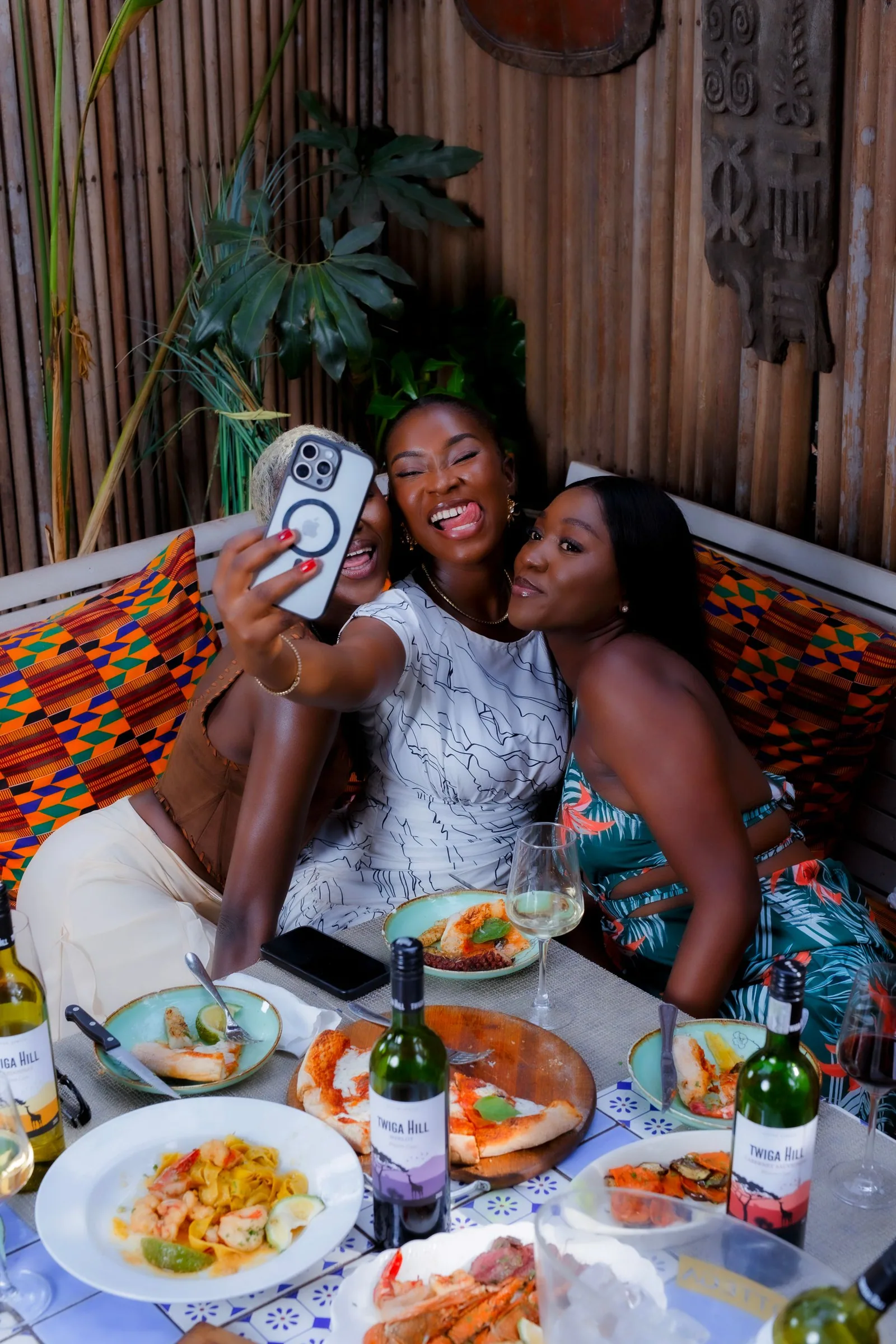 Three friends taking a photograph together over dinner in Accra